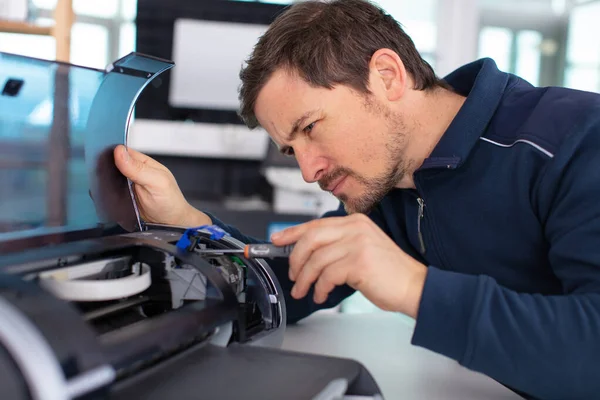 man repairs a domestic printer in the workshop