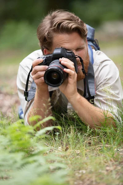 Männlicher Fotograf Liegt Auf Dem Gras Und Fokussiert Die Kamera — Stockfoto