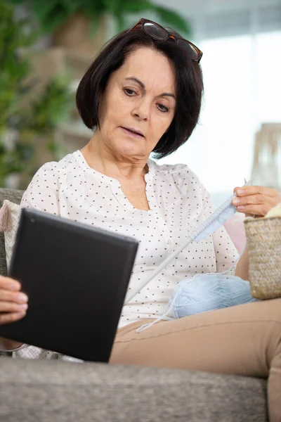 Senior Woman Seduta Sul Divano Con Filati Aghi Tablet — Foto Stock