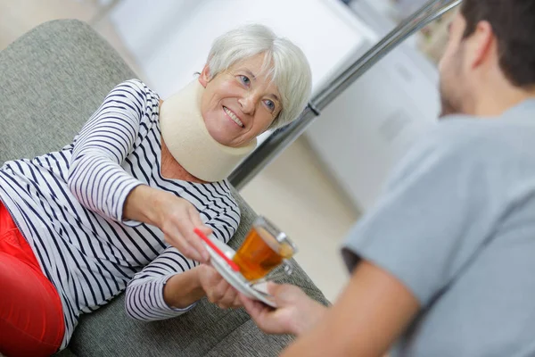Молодой Человек Дому Помогает Напоить Чаем Пожилую Женщину — стоковое фото