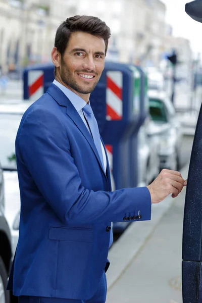 Glücklicher Junger Geschäftsmann Steckt Münze Parkautomat — Stockfoto
