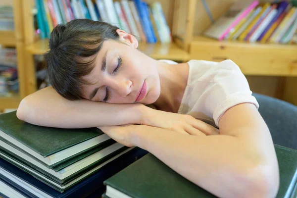 Kütüphanedeki Kitap Yığınının Üzerinde Uyuyan Genç Bayan — Stok fotoğraf