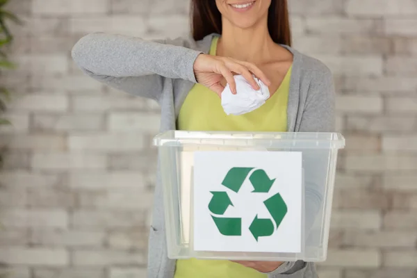woman recycling paper in recycling bin