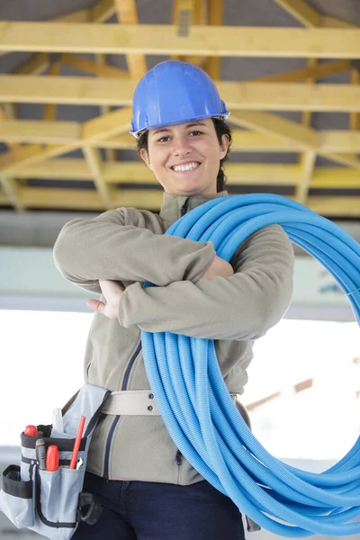 充满热情的女建筑工人拿着一卷蓝色管子 — 图库照片
