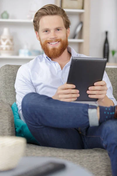 Homem Feliz Sofá Segurando Tablet Nas Mãos — Fotografia de Stock