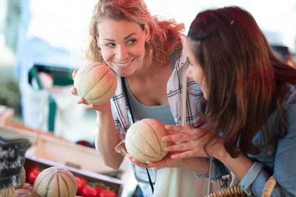 妇女们站在食品市场旁举起新鲜的甜瓜 — 图库照片