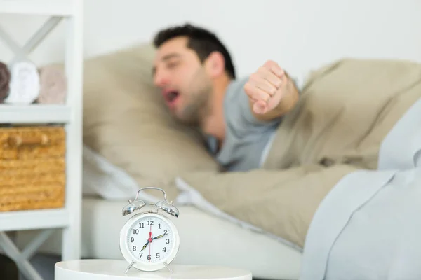 Man Stretching Sängen Alarmklocka Förgrunden — Stockfoto
