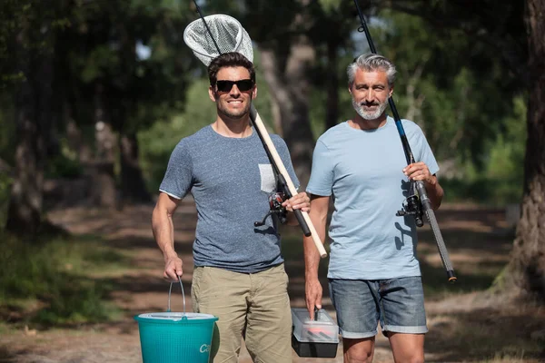 湖の近くで釣り道具を持って歩く男たち — ストック写真