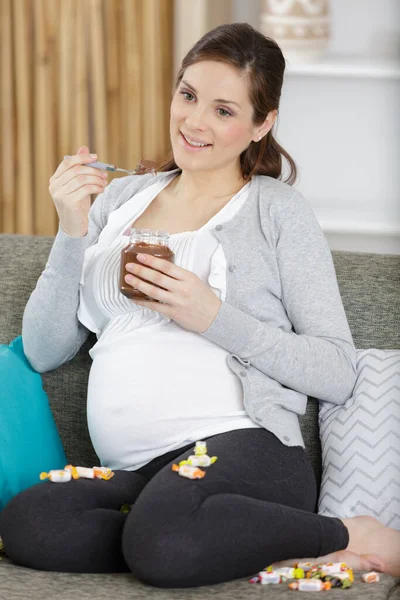 妊娠中の女性が瓶から広がるチョコレートを食べ — ストック写真