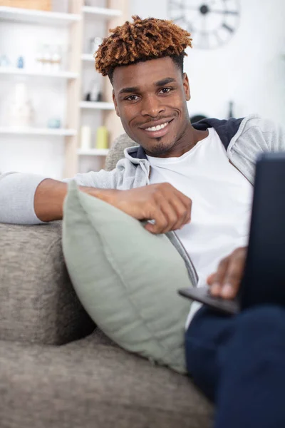 Ευτυχισμένος Νεαρός Άνδρας Που Χρησιμοποιεί Φορητό Υπολογιστή Στον Καναπέ — Φωτογραφία Αρχείου