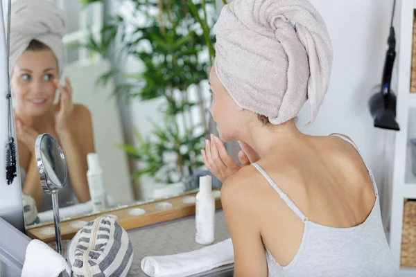 鏡の前で美容製品を適用する女性 — ストック写真