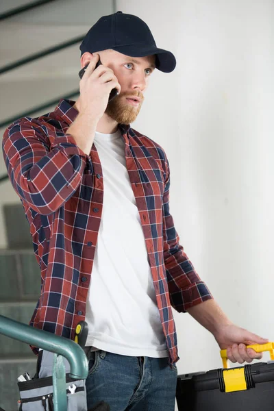 Elektryk Korzystający Telefonu Komórkowego Podczas Rozmowy Klientem — Zdjęcie stockowe