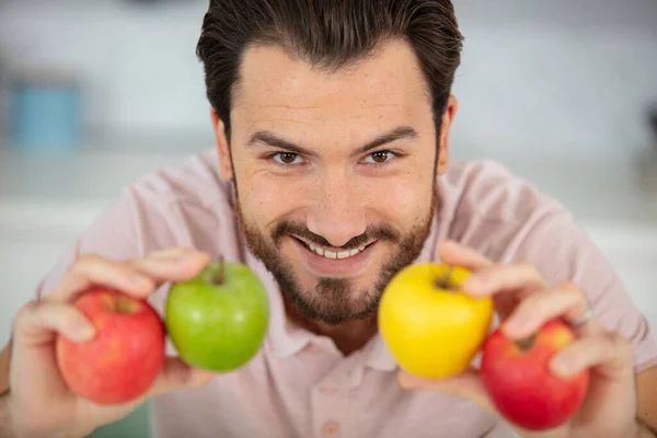 man holding four apples to the camera