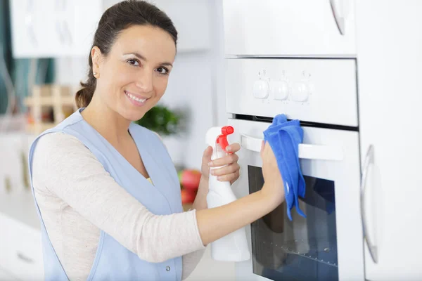 一个快乐的女人在打扫烤箱 — 图库照片