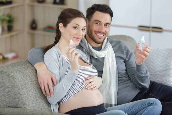 妊娠中のカップルは青いボトルとピンクのボトルを — ストック写真