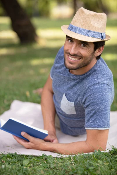Homem Sorrindo Deitado Parque Lendo Livro — Fotografia de Stock