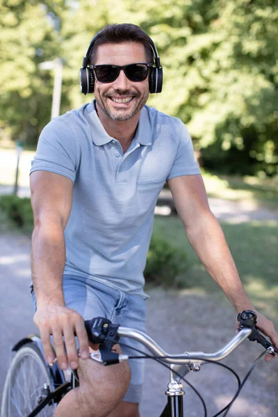 男人在骑自行车上下班时喜欢用耳机听音乐 — 图库照片