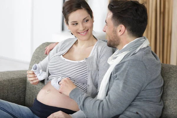 Schwangere Sitzt Mit Babyschuhen Auf Sofa — Stockfoto