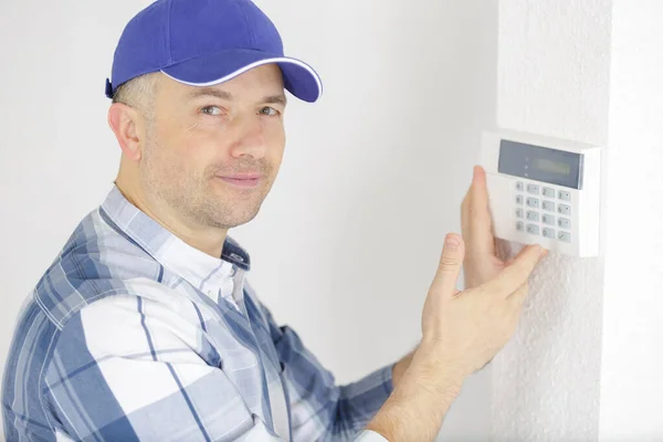 男性電気技師が壁にセキュリティシステムドアセンサーを設置し — ストック写真