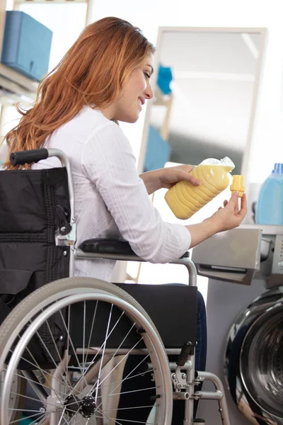 Kobieta Wózku Inwalidzkim Przez Pralka Wylewanie Odżywki Tkaniny — Zdjęcie stockowe