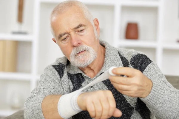 Man Bandaging His Own Hand — Stock Photo, Image