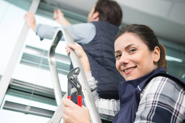 若い笑顔の女性がはしごで同僚を助け — ストック写真