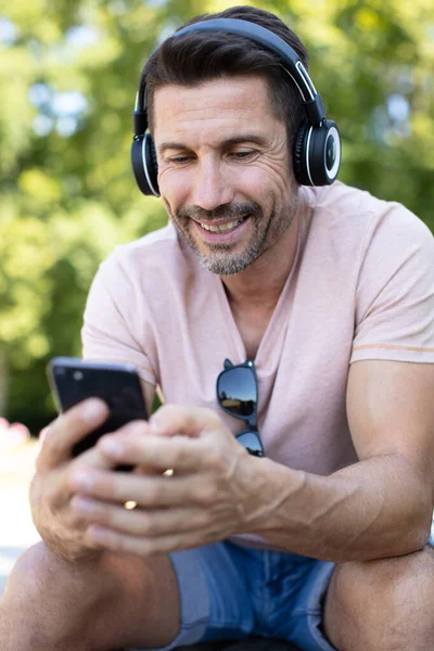 Middle Aged Man Wearing Headphones Using Smartphone — Stock Photo, Image