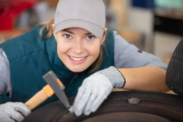 Female Mechanic Using Hammer While Working Tyre — Foto de Stock