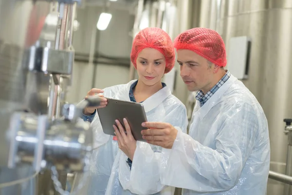 Brauereiarbeiter Mit Haarnetzen Blicken Auf Tablet Bildschirm — Stockfoto