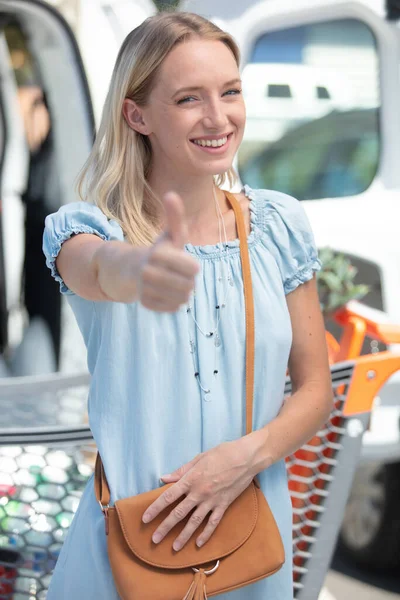 ショッピングカートに乗って親指を立てる幸せな女性 — ストック写真