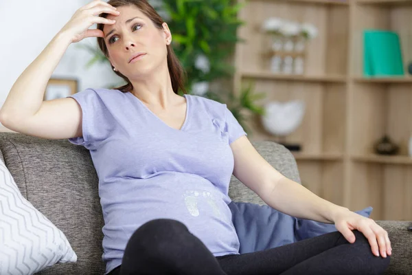 ソファの上に座って心配して妊娠中の女性 — ストック写真