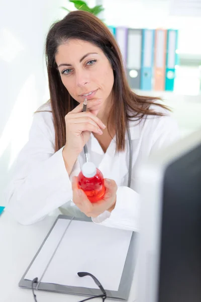 Kadın Doktor Şişedeki Kırmızı Ilacı Düşünüyor — Stok fotoğraf