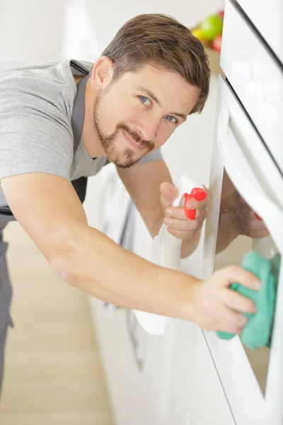 幸せな若い男です制服掃除電子レンジでキッチン — ストック写真