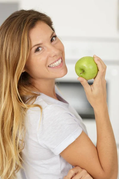 幸せな女性が緑のリンゴを噛み — ストック写真