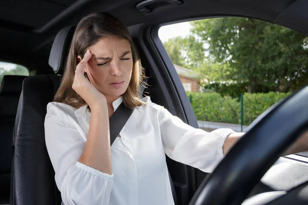 female driver wincing from a headache