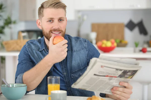 Man Reading Newspaper While Eating Meal Home — Stockfoto