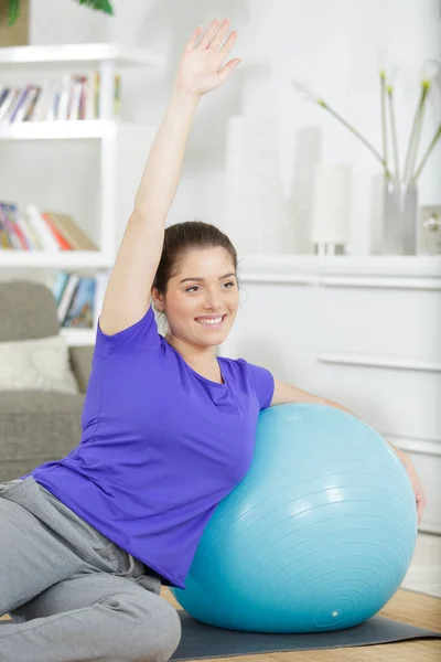 快乐的女人 蓝色合适的球坐在瑜伽垫上 — 图库照片