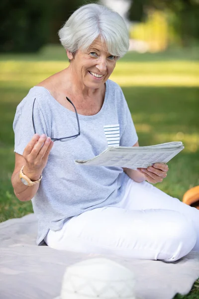 在毛毯杂志上笑着的老年妇女 — 图库照片