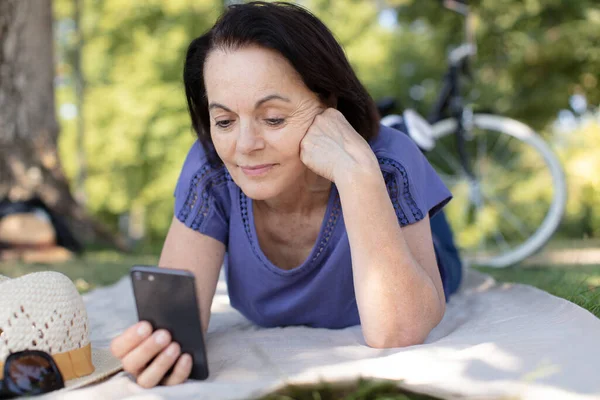 公園で携帯電話で話す幸せな成熟した女性は — ストック写真