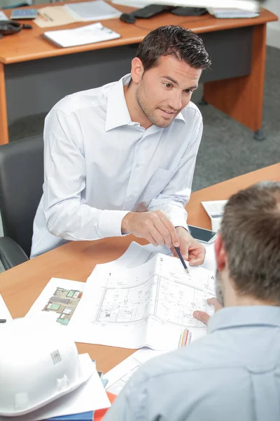 Mann Zeigt Auf Pläne Büro — Stockfoto