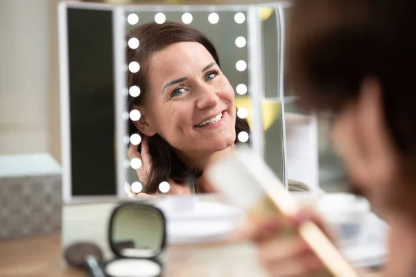 Donna Spazzolando Capelli Guardando Uno Specchio Illuminato — Foto Stock