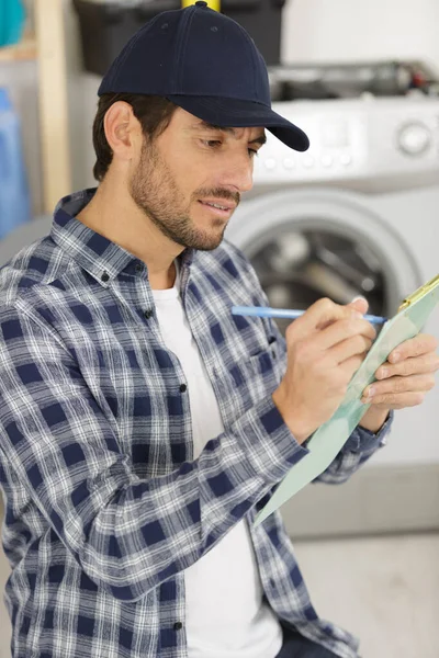 technician with clipboard near washing machine
