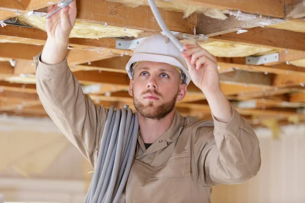 戴头盔固定电缆的男性建筑工人 — 图库照片