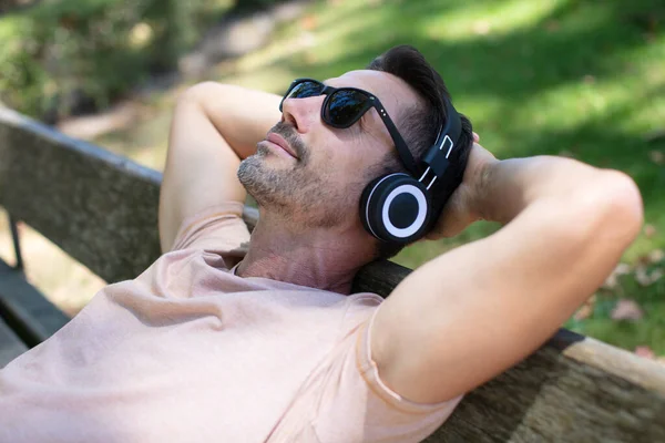 Człowiek Słuchając Muzyki Siedzi Ławce — Zdjęcie stockowe