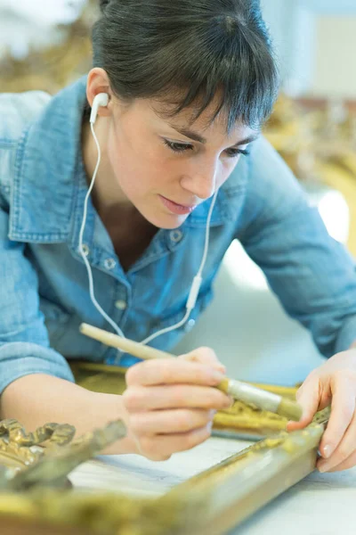 Vrouwelijke Werknemer Luisteren Naar Koptelefoon Tijdens Het Schilderen Frame — Stockfoto