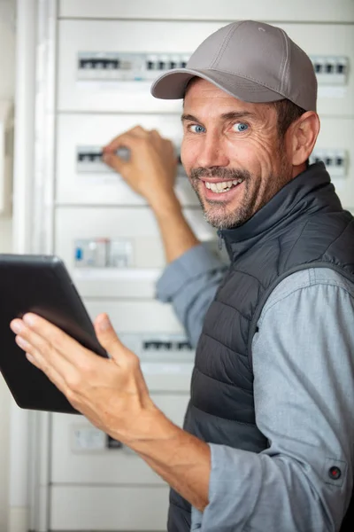 Male Electrician Holding Tablet Working Fuse Box — Stock Photo, Image