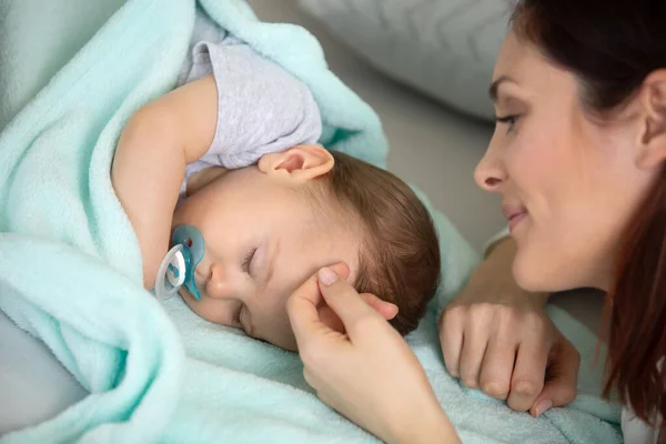 ベッドの上に寝そべっている母親と赤ん坊 — ストック写真