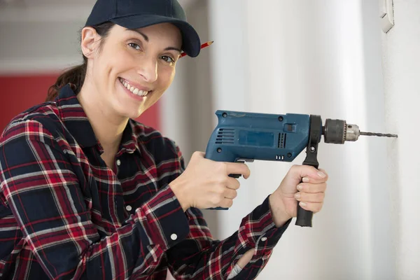 beautiful woman drilling wall during renovation of home