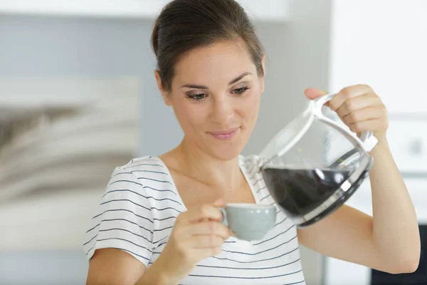 魅力的な女性がフィルターコーヒーをカップに注ぎ — ストック写真