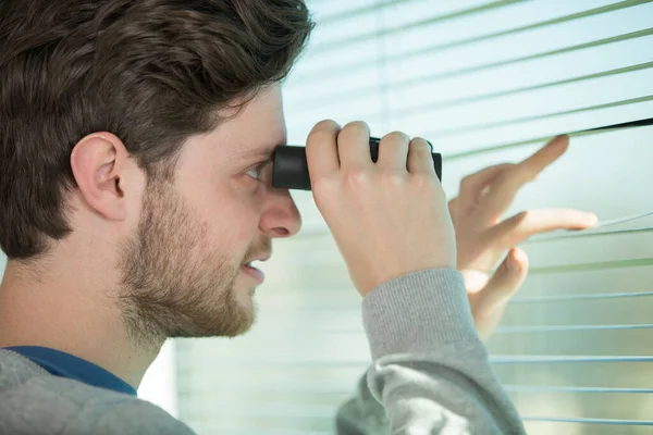 Junger Mann Steht Und Schaut Mit Fernglas Durch Ein Glasfenster — Stockfoto